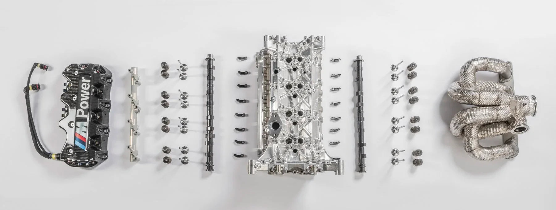 Exploded BMW M Power cylinder head with camshafts, valves, springs and exhaust manifold