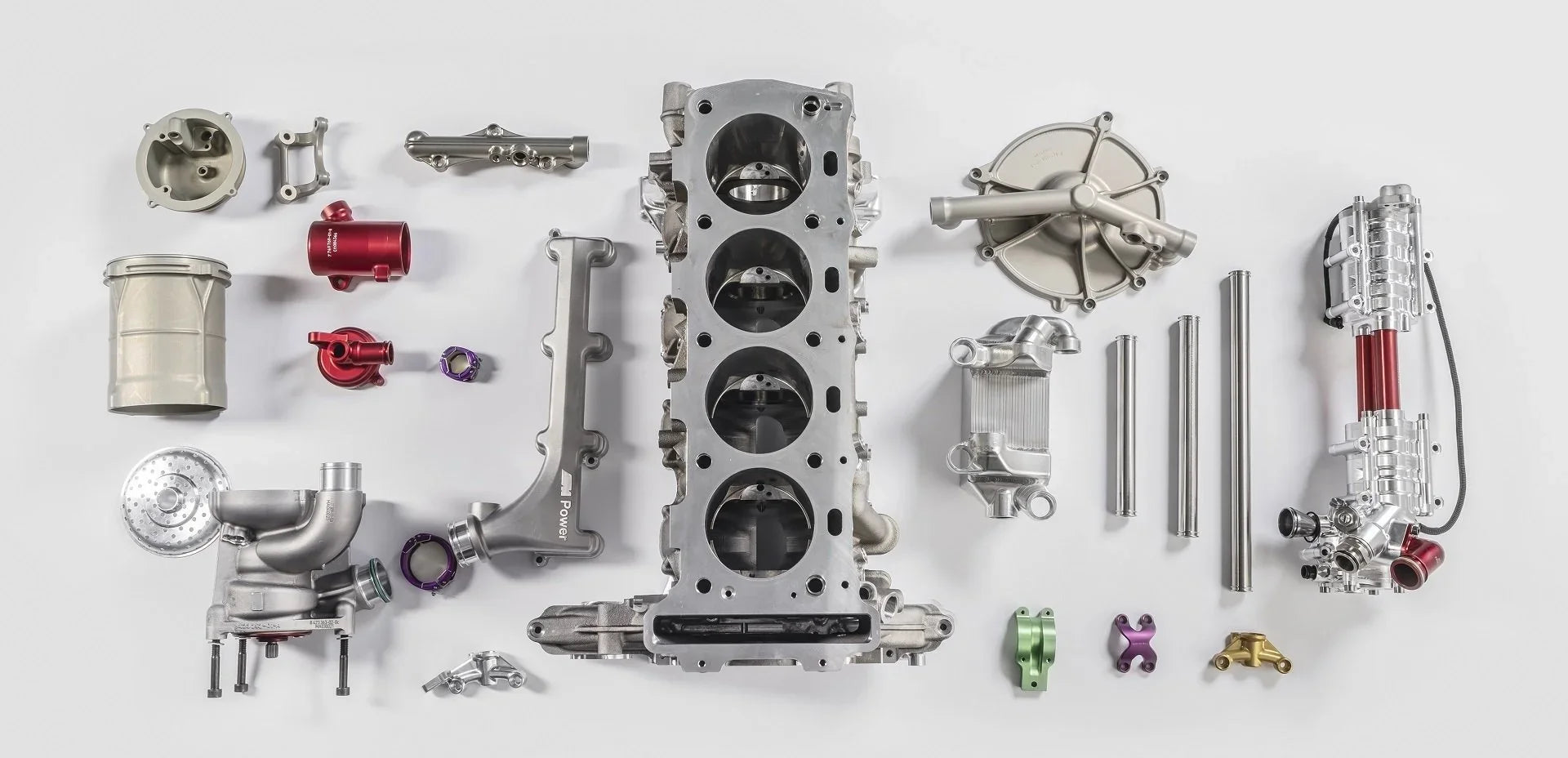 Disassembled engine laid flat, four-cylinder block centre, turbo and covers around it